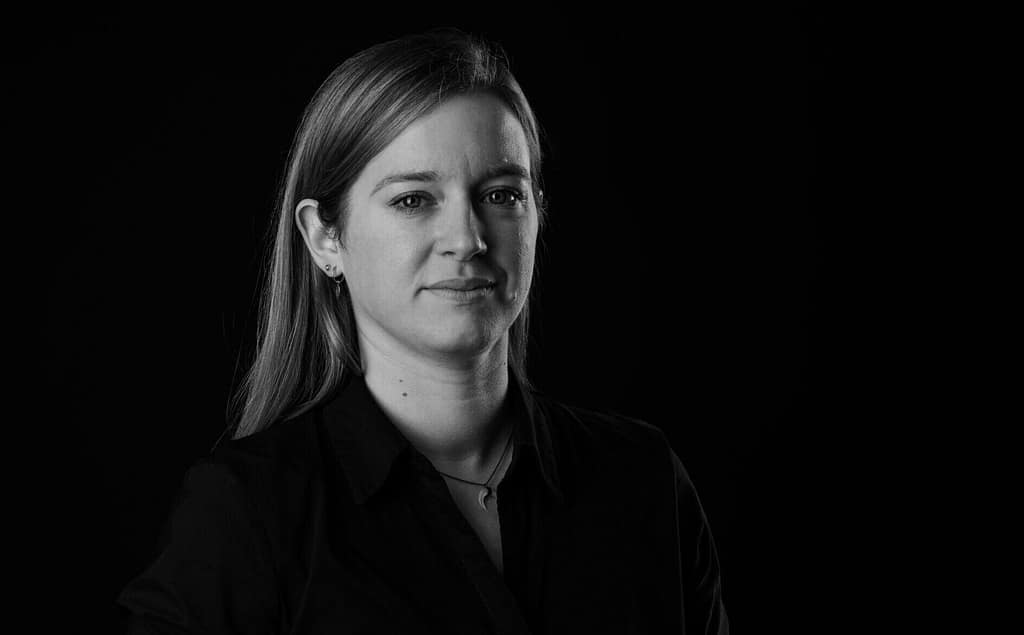 Ein schwarz-weiß Porträt von Katja Jansen, einer jungen Frau mit langen Haaren, die freundlich in die Kamera schaut.
